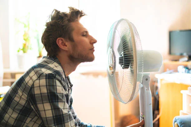 A person relaxing in a room with a fan on a humid day